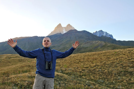 hiker with binoculars stands on a background of mountains. Svaneti, Georgia