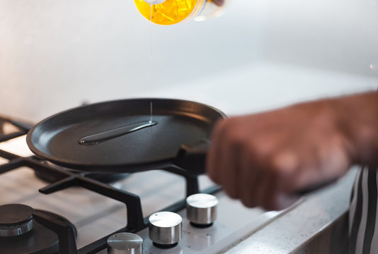 A man cook in a nice apron prepares an omelette in a frying pan on a glass gas hob
