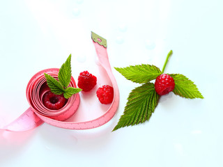 Measuring tape wrapped around a ripe raspberry / Health concept, diet. Fresh with leaves, healthy lifestyle, healthy food