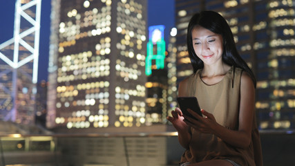 Woman reading on smart phone in city