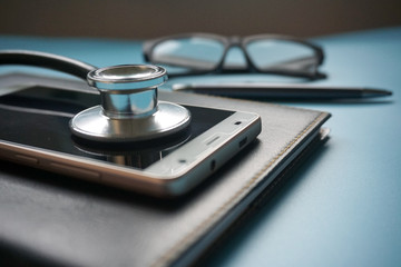 Health and Business Concept. Stethoscope and smartphone on organizer.
