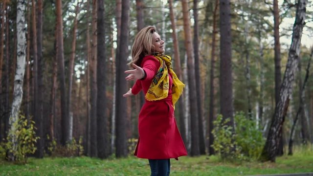 beautiful young woman enjoying warm autumn day and a fun spinning in the autumn forest. slow motion