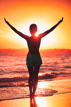 Freedom woman with open arms silhouette in sunrise against sun flare. Morning yoga girl practicing sun salutation outdoors. Carefree person living a free life. Success freedom happy life concept.