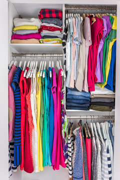 Home closet organized walk-in bedroom wardrobe of women fashion clothes hanging on racks. Summer style, dresses and t-shirts