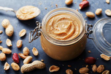 Peanut butter jar and heap of nuts on vintage table. - Powered by Adobe