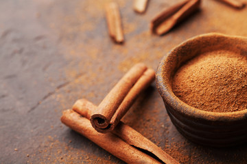 Organic cinnamon sticks and powder on brown rustic background. Aromatic spices.