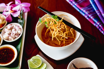 A beautiful set of Khao Soi, local northern food of Thailand. Khao soi is checken with curry with crispy noodle on top. Eat with traditional side dishes.