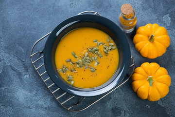 Freshly made pumpkin cream-soup on a blue stone background, high angle view