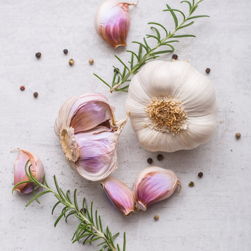 Garlic. Garlic bulbs. Fresh garlic with rosemary and pepper on white concrete board