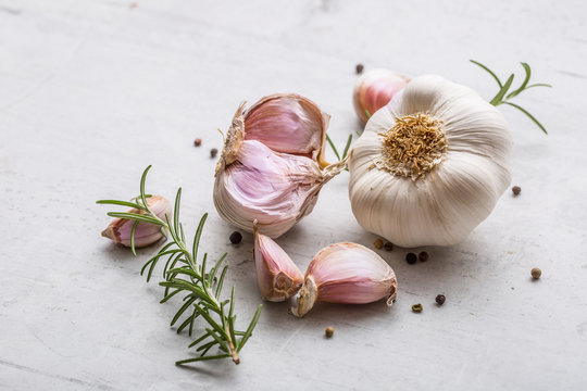 Garlic. Garlic bulbs. Fresh garlic with rosemary and pepper on white concrete board