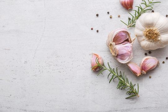 Garlic. Garlic bulbs. Fresh garlic with rosemary and pepper on white concrete board