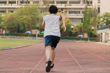 Fototapeta premium Vintage filter image of back view of young Asian sprinter leaving starting on racetrack at athletics stadium.