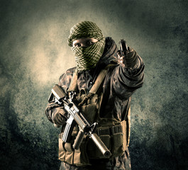 Fototapeta na wymiar Portrait of a heavily armed masked soldier with grungy background