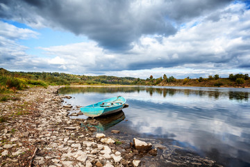 Old boat on the river bank, beautiful scenery with dramatic clouds