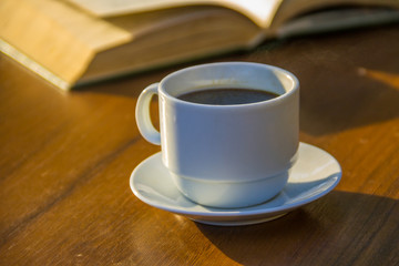 Cup of coffee and book on wooden table