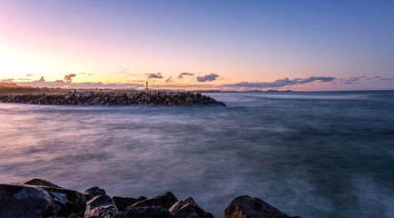 Bunswick heads pier at dusk with the sunset in the background. The pink and purple sky is reflecting in the water coming into the heads.