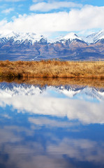 Beautiful autumn landscape with reflection of snow-capped mountains in lake water