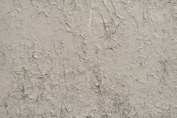 White-gray surface of a wall with cracked paint, plaster, close-up 