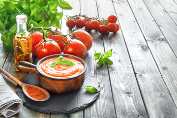 Tomato cream soup in ceramic bowl served with cream and basil, space