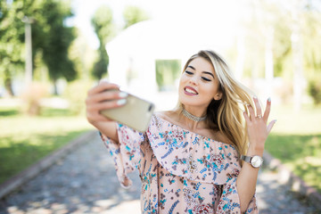 POrtrait of a smiling young girl making selfie photo phone in park