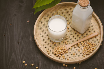 Bottle of soy milk and soybean on wooden table