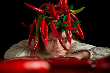 Portrait of a girl with a haircut from red chili peppers at a table on which lie long red peppers.