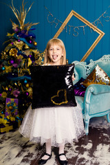 smiling girl with a pillow against the Christmas tree background