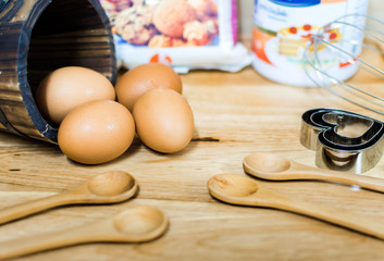 flour with egg and ingredients for homemade bakery on wooden background