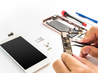 Close-up of technician hand clamping processor on smartphone logic board on smartphone component background with copy space