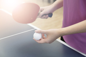 woman playing table tennis with the racket and ping pong ball in serving position