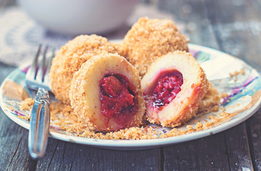 Plum dumplings on colorful plate on wooden background