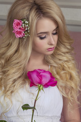 Blonde with long hair in a white dress and with a rose in your hands 