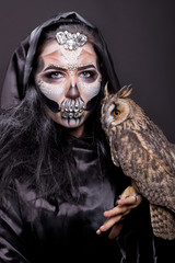 girl with a make-up for halloween with an owl in hands