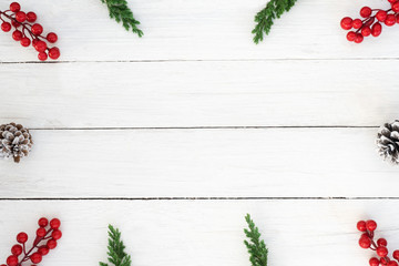 Christmas background. Christmas frame made of fir leaves, pine cones and holly berry decoration rustic elements on white wooden. Creative flat lay, top view design