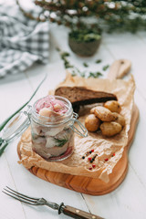 herring, homemade pickles with baked potatoes and onions on wooden Board