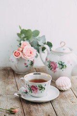 tea set in composition with flowers and marshmallows. Coffee mug on a saucer, a teapot and a sugar bowl. Filmed in the interior
