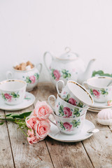 tea set in composition with flowers and marshmallows. Coffee mug on a saucer, a teapot and a sugar bowl. Filmed in the interior