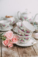 tea set in composition with flowers and marshmallows. Coffee mug on a saucer, a teapot and a sugar bowl. Filmed in the interior