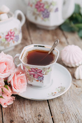 tea set in composition with flowers and marshmallows. Coffee mug on a saucer, a teapot and a sugar bowl. Filmed in the interior