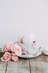 tea set in composition with flowers and marshmallows. Coffee mug on a saucer, a teapot and a sugar bowl. Filmed in the interior
