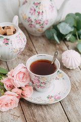 tea set in composition with flowers and marshmallows. Coffee mug on a saucer, a teapot and a sugar bowl. Filmed in the interior