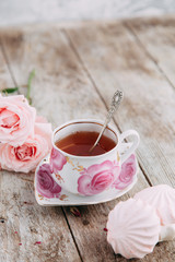 tea set in composition with flowers and marshmallows. Coffee mug on a saucer, a teapot and a sugar bowl. Filmed in the interior