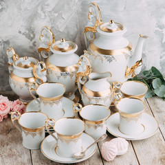 tea set in composition with flowers and marshmallows. Coffee mug on a saucer, a teapot and a sugar bowl. Filmed in the interior