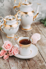 tea set in composition with flowers and marshmallows. Coffee mug on a saucer, a teapot and a sugar bowl. Filmed in the interior