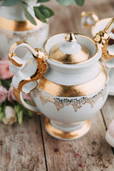tea set in composition with flowers and marshmallows. Coffee mug on a saucer, a teapot and a sugar bowl. Filmed in the interior