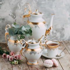 tea set in composition with flowers and marshmallows. Coffee mug on a saucer, a teapot and a sugar bowl. Filmed in the interior