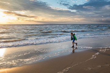 Boy running on beach at sunset