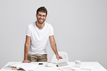 Cheerful stylish male freelancer being glad to have successful day, rejoices finishing work, stands...
