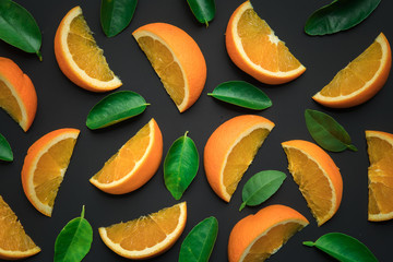 Colorful fruit of fresh orange slices with leaf on black background.