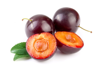 Purple plums end half with leaves isolated on white background